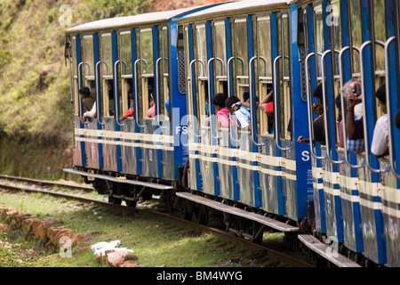 I viaggiatori guardare fuori delle finestre aperte del calibro di stretta Nilgiri ferrovia di montagna come si inerpica il Nilgiri Hills in India. Foto Stock