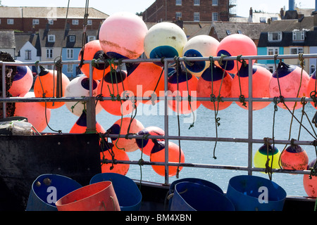 Parafanghi in barca e di boe sul lato di un peschereccio attraccato a Weymouth Foto Stock