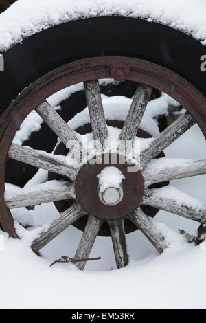 La neve copre un trattore abbandonato il carro in legno del mozzo della ruota di un veicolo antico in una fattoria in Finlandia Foto Stock