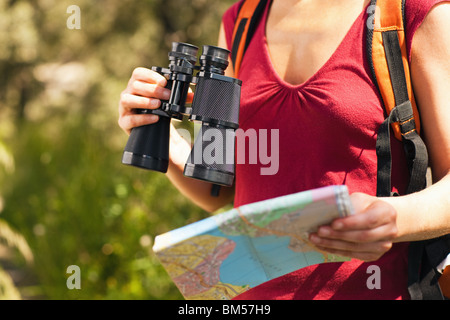 Vista ritagliata della femmina di bird watcher tenendo il binocolo e la mappa. Foto Stock