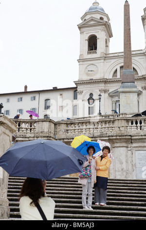 Turisti asiatici prendere una foto nella Trinità de monti in inverno Rainy day ombrelli sotto la pioggia. Roma Italia Europa Foto Stock