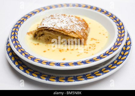 Strudel di mele (Apfelstrudel) è servita con crema pasticcera (Vanillesoße) in Baviera, Germania. Foto Stock