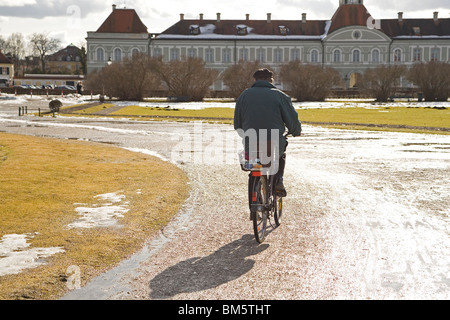 Un uomo più anziano cavalca la sua bicicletta nel parco del palazzo di Nymphenburg a Monaco di Baviera, Germania. Foto Stock