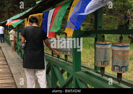 Girare le ruote di preghiera sul lungomare dal lago di Khecheopalri, lago sacro in Sikkim. Foto Stock