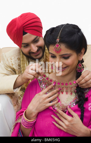 Uomo a mettere su una collana nella sua moglie il collo Foto Stock