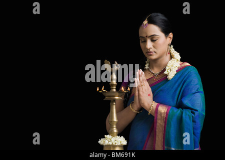 Donna che prega davanti a una lampada ad olio Foto Stock