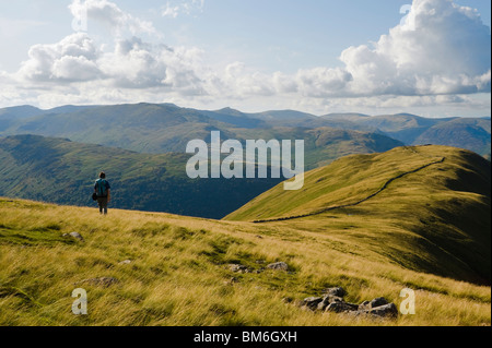 Il camminatore solitario sulla cresta sopra Hartsop Dodd, Lake District, con Helvellyn all'orizzonte Foto Stock