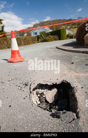 Un foro di apertura fino in strada a Ambleside, a causa indeboliti dalle acque di esondazione. Foto Stock