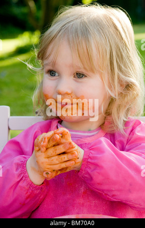 Ragazza TODDLER, gode di ottenere confuso mentre mangi la pasta in salsa di pomodoro Foto Stock