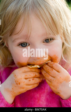 Ragazza TODDLER, gode di ottenere confuso mentre mangi la pasta in salsa di pomodoro Foto Stock