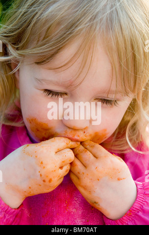 Ragazza TODDLER, gode di ottenere confuso mentre mangi la pasta in salsa di pomodoro Foto Stock