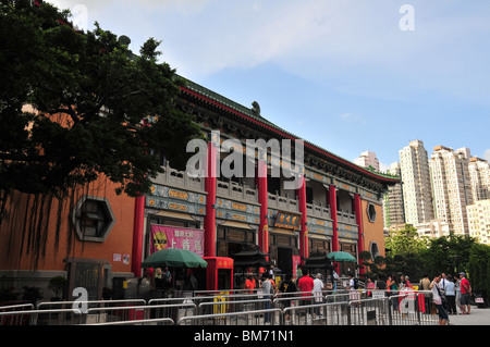 La folla di fedeli al di fuori delle colonne di rosso e oro sculture di Shenseng Hall, Wong Tai Sin Temple, Hong Kong Foto Stock