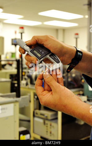 Operaio di fabbrica utilizzando il micrometro per misurazioni di controllo Foto Stock