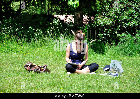 Giovane donna che studiano in Park, Hyde Park, City of Westminster, Londra, Inghilterra, Regno Unito Foto Stock