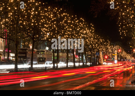 In scena con il traffico in movimento e gli alberi decorati con luci, Unter den Linden, Berlino, Germania Foto Stock