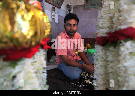 Un uomo che fa ghirlande di fiori nel mercato Devaraja a Mysore, Karnataka, India. Foto Stock