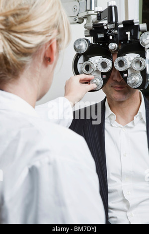 Un all'ottico optometrista condurre un esame oculistico su un uomo Foto Stock