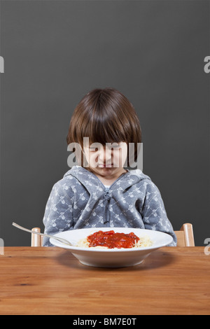 Ragazzo che guarda verso il basso in corrispondenza di una ciotola di spaghetti in disgusto, studio shot Foto Stock