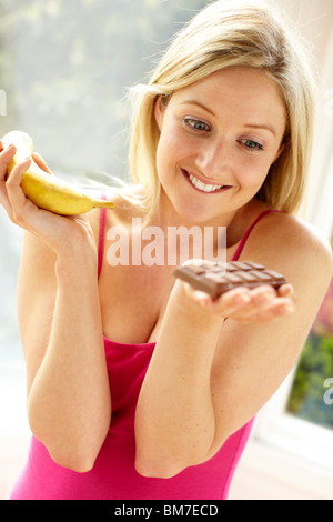 Donna di decidere tra frutta e cioccolata Foto Stock
