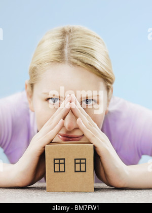 Una donna di mani rendendo un campanile su una casa di cartone Foto Stock