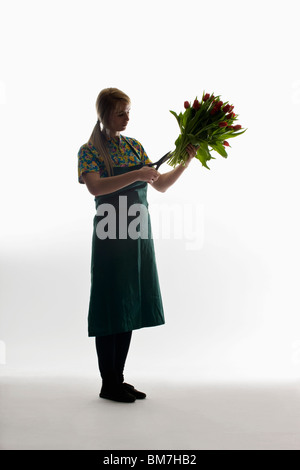 Un fiorista fresare i gambi di un mazzo di tulipani Foto Stock