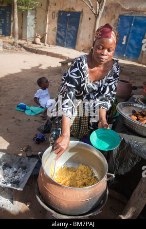 Una donna vende la frittura di banane da cuocere (alloco) e patate per la colazione vicino alla stazione degli autobus di Segou, Mali. Foto Stock