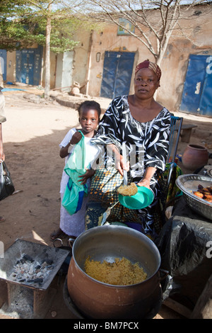 Una donna vende la frittura di banane da cuocere (alloco) e patate per la colazione vicino alla stazione degli autobus di Segou, Mali. Foto Stock