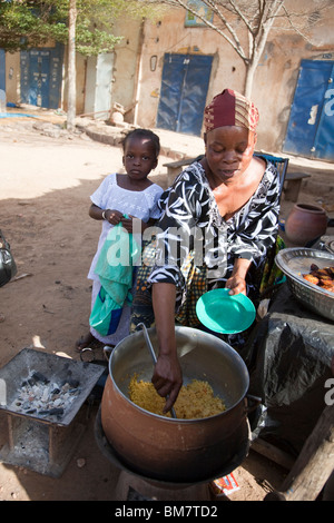 Una donna vende la frittura di banane da cuocere (alloco) e patate per la colazione vicino alla stazione degli autobus di Segou, Mali. Foto Stock