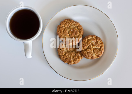 White tazza di caffè nero e tre cioccolato Biscotti friabili su una piastra bianca Foto Stock