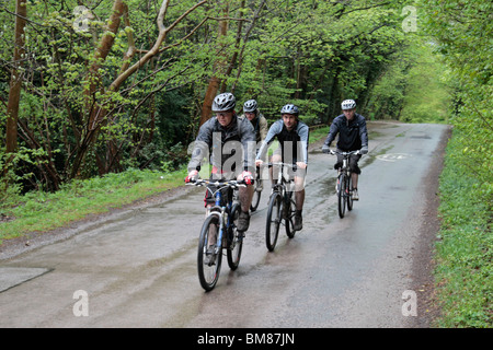 Quattro i ciclisti di montagna su una strada bagnata vicino Wendover, Chiltern Hills, Buckinghamshire, UK. Aprile 2010. Foto Stock