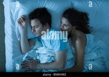 Coppia insieme a letto, donna che comprenda l'uomo, guardando a lui il sonno Foto Stock