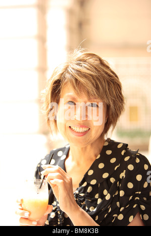 Ritratto di donna matura azienda vetro, sorridente Foto Stock