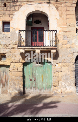 San Lawrenz, Gozo, Malta. Una vecchia porta verde al di sotto di un tradizionale balcone Maltese. Data di pietra con croce, 1806 Foto Stock