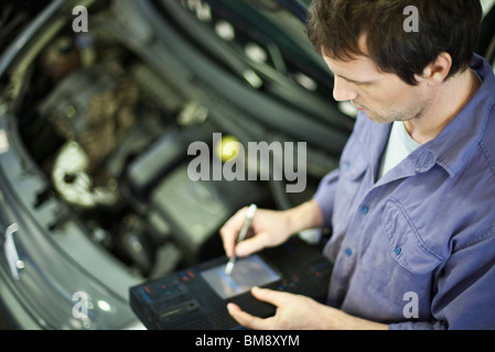 Mechanic utilizzando gli strumenti elettronici per la valutazione delle prestazioni delle automobili Foto Stock