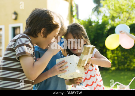 Ragazzo regalo di apertura alla festa di compleanno come amici guardare Foto Stock