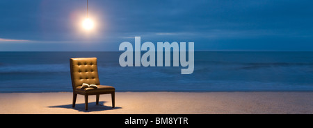 Lampadina accesa sulla sedia con il libro aperto sulla spiaggia di notte Foto Stock