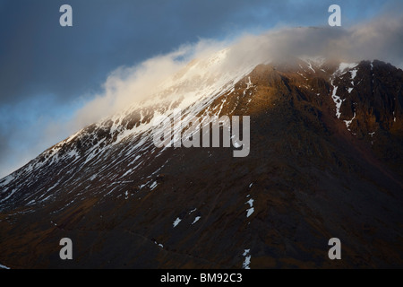 Chiudere l immagine della parte superiore del grande timpano in montagna gli ultimi raggi del sole serale con il cloud aggrappandosi al picco innevato Foto Stock