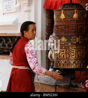 Signora hilltribe determina la rotazione di una ruota di preghiera(Khor),a boudhanath ,uno del santissimo siti buddista a Kathmandu in Nepal Foto Stock