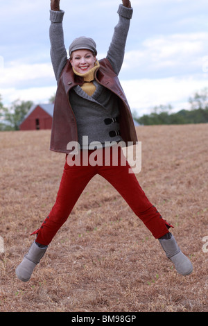 Donna gioiosa saltando in esecuzione in autunno inverno Foto Stock