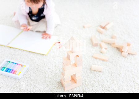 Baby girl disegno accanto alla costruzione in legno blocchi Foto Stock