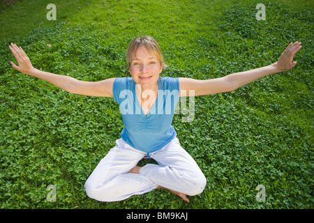 Donna fare yoga su un prato verde Foto Stock