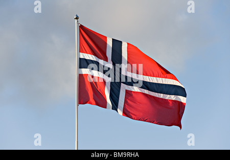 Bandiera norvegese vola orgogliosamente in una brezza da un pennone in un cielo blu chiaro Foto Stock