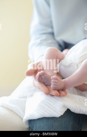 Padre tenendo i piedi di due settimane vecchio baby Foto Stock