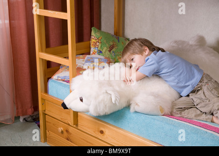 5 anno vecchio ragazzo giace sul letto a castello con orso polare peluche Foto Stock