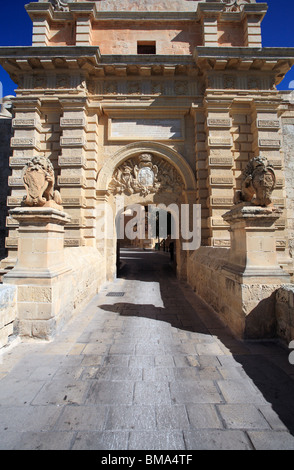 La porta di Mdina, Mdina, Malta che mostra l'arco e bracci/crest sopra con i due leoni su pilastri di pietra su entrambi i lati del ponte Foto Stock