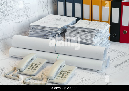Grandi mucchi di progettazione e disegni, cartella e due telefoni sulla superficie del tavolo. White whatman sono lo sfondo. Foto Stock