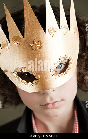 Ragazzo che indossa corona d'oro maschera Foto Stock