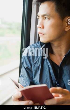 L'uomo la lettura di un libro sul treno Foto Stock