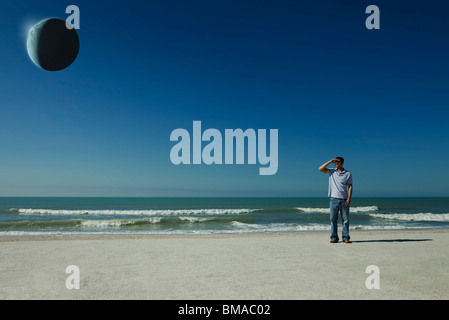 Uomo sulla spiaggia osservando eclipse Foto Stock