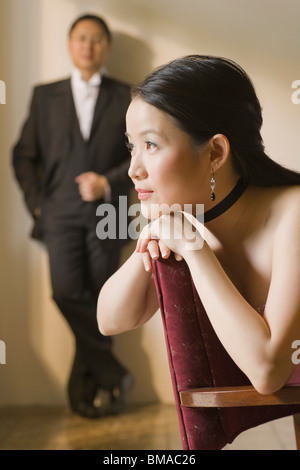 Donna fantasticando con uomo in piedi in background Foto Stock